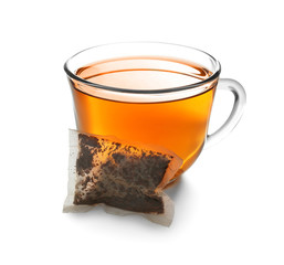 Cup with delicious tea and used bag on white background