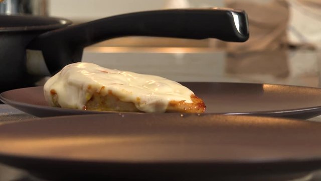 Meat with cheese is put on a plate - closeup