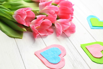 Beautiful tulips and decorative felt hearts on white wooden background