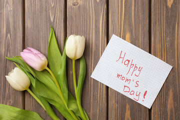 Beautiful tulips and handmade card for Mother's Day on wooden background, top view