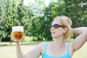Portrait of happy woman holding glass of beer outside on sunny day.