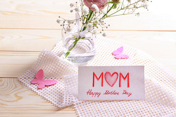 Flowers and handmade card for Mother's Day on wooden table