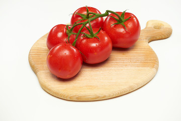 Several tomatoes lie on a wooden cutting board.