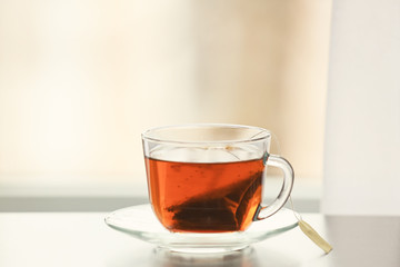 Glass cup of tasty hot tea on table