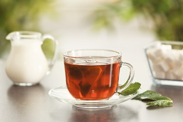 Glass cup of tasty hot tea on table