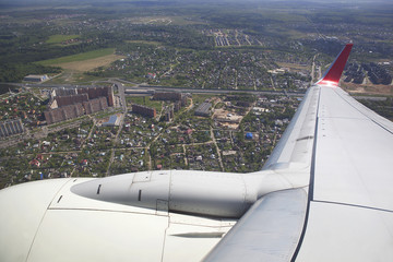 Wing of the aircraft over the city and houses.