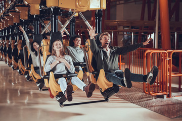 Fototapeta na wymiar Friends ride on swing in amusement park.