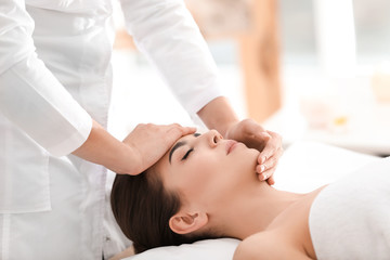 Fototapeta na wymiar Young woman enjoying facial massage in spa salon