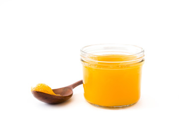 Ghee or clarified butter in jar and wooden spoon isolated on white background