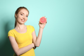 Beautiful young woman with citrus fruit on color background