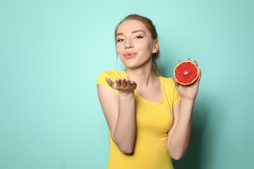 Beautiful young woman with citrus fruit on color background