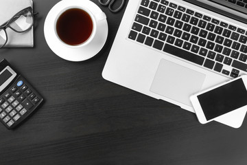 Laptop, cup of coffee and smartphone on dark background, flat lay. Workplace table composition