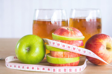 fresh green and red apple slice and juice glasses with measuring tape, healthy fruit and drink for weight control in summer