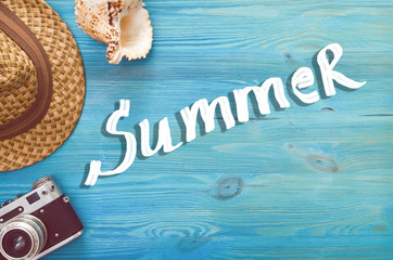 Summer background with copy space. Retro photo camera, seashell and hat on blue wooden background.