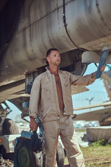 Fototapeta na wymiar Mechanic in uniform standing near a war fighter-interceptor in an open-air museum.