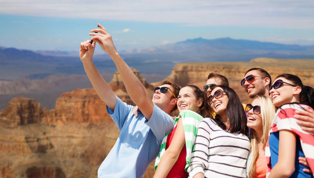 travel and tourism concept - group of happy friends taking selfie by cell phone over grand canyon national park background