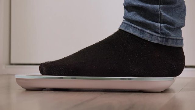 A woman stands on a digital scale - closeup from the side