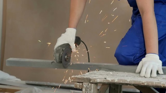Industrial worker cutting metal with many sharp sparks at construction site