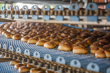 Cakes on automated round conveyor machine in bakery food factory, production line