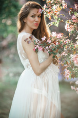 Obraz na płótnie Canvas Pregnant pretty woman is posing in pink apple garden