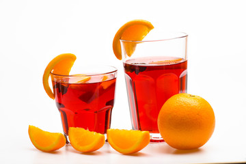 Cocktail concept. Glasses with orange drink near juicy orange fruit on white background, close up. Drink or beverage with orange. Cocktail or beverage with orange juice