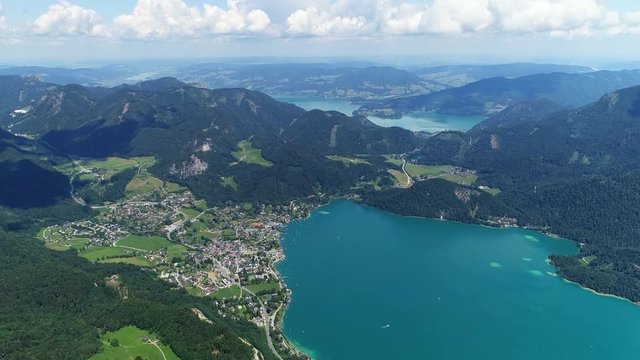 Aerial panoramic view of lake Wolfgangsee in summer, scenery with majestic lush green slopes and peaks of Alps mountains, alpine town St Gilgen - picturesque landscape of Austria from above, Europe