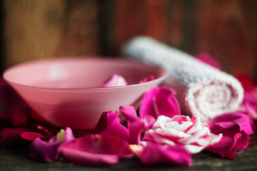 Obraz na płótnie Canvas Bowl with water and rose petals on wooden table