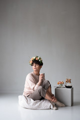 woman having coffee at home wearing a romantic flower crown in her hair