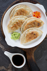 White plate with fried korean potstickers and dipping sauces, view from above, vertical shot, closeup
