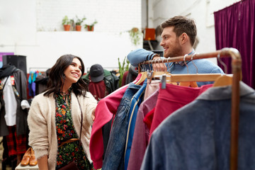 sale, shopping, fashion and people concept - happy couple at vintage clothing store hanger
