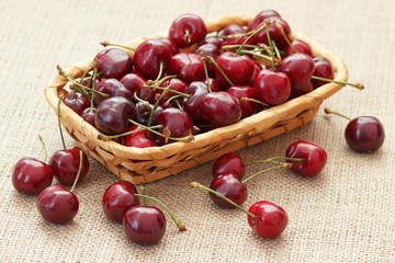 Merry cherries berries in wicker dish on burlap textile background