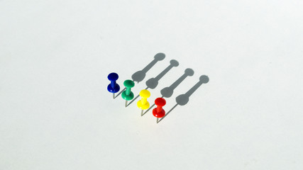 four colorful push pins with shadow on white background