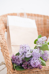 Lilac spring bouquet and craft bag on natural wooden chair