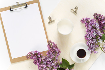 Flat lay with pad, paper, clips, coffee and lilac