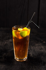 Ice tea cocktail with lime on black background