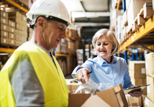 Senior woman manager and man worker working in a warehouse.