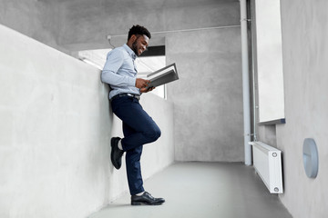 business, people and corporate concept - smiling african american businessman with folder at office