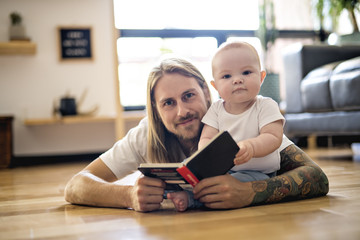 father with her baby and a book in the living room