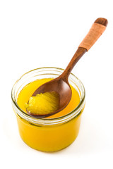 Ghee or clarified butter in jar and wooden spoon isolated on white background