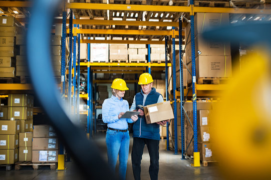 Senior managers or supervisors with tablet working in a warehouse, controlling stock.