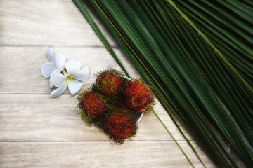 Rambutan and frangipani flowers with a palm leaf. Fresh Tropical Fruits