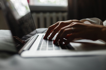 Young attractive and beautiful happy european woman 20s lying in bed at home using internet working on computer laptop smiling relaxed and cheerful at her bedroom in morning lifestyle concept.