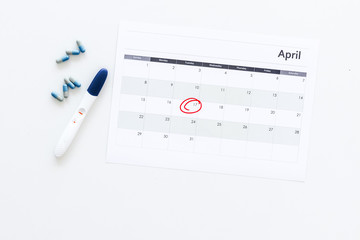 Planning pregnancy. Positive pregnancy test near calendar page and pills on white background top view space for text