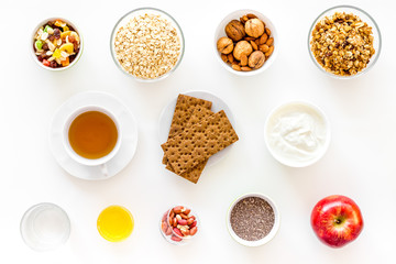 Obraz na płótnie Canvas Ingredients for healthy breakfast. Fruits, oatmeal, yogurt, nuts, crispbreads, chia on white background top view