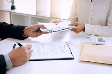 Bribery and corruption concept, bribe in the form of dollar bills, Businessman giving money in the envelope while making deal to agreement a real estate contract and financial corporate