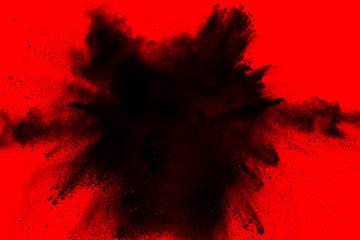 Black powder dust explosion isolated on red background.