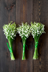 May flowers. Bouqet of lily of the valley flowers on dark wooden background top view copy space