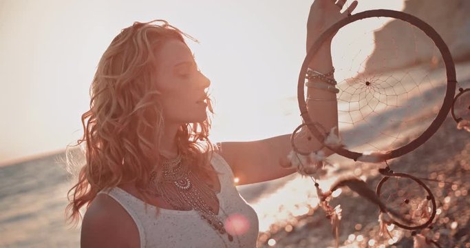 Young woman in boho style with dreamcatcher at beach