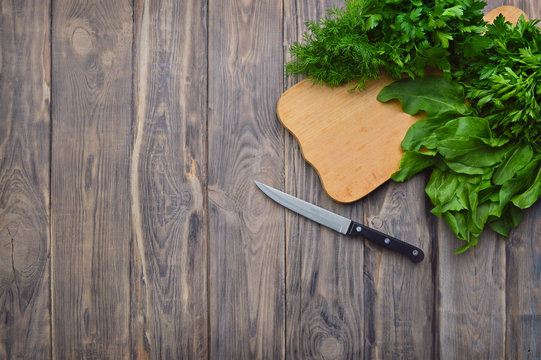 Fresh parsley , dill, spinach, sorrel on a cutting board and a knife. cooking. Healthy eating. Greenery. Top view. The concept of a healthy diet.
