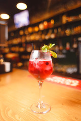 A cool alcoholic cocktail is on a wooden bar counter